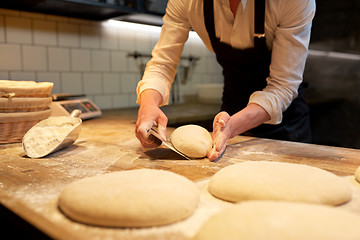 Image showing baker portioning dough with bench cutter at bakery