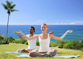 Image showing couple doing yoga in lotus pose outdoors