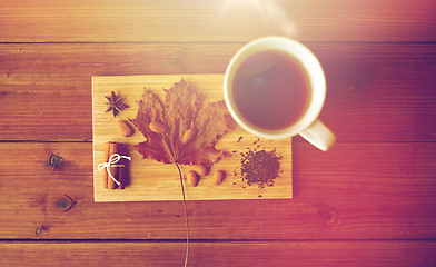 Image showing cup of tea, maple leaf and almond on wooden board