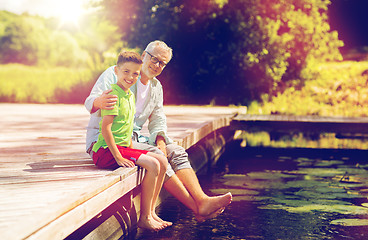 Image showing grandfather and grandson sitting on river berth