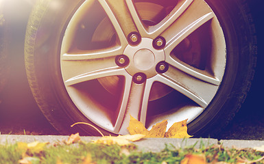 Image showing close up of car wheel and autumn leaves