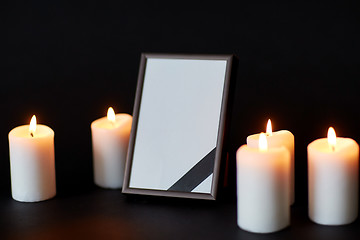 Image showing black ribbon on photo frame and candles at funeral