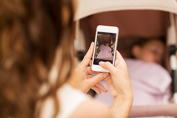 Image showing mother with smartphone and stroller at park