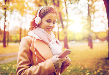 Image showing woman with smartphone and earphones in autumn park