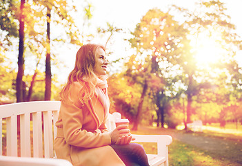 Image showing happy young woman drinking coffee in autumn park