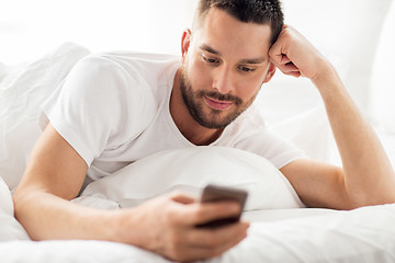 Image showing close up of man with smartphone in bed in morning