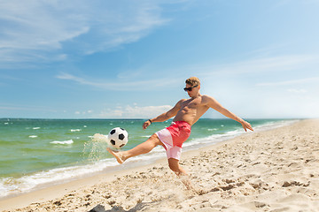 Image showing young man with ball playing soccer on beach