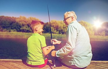 Image showing grandfather and grandson fishing on river berth