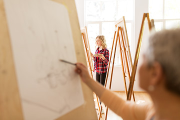 Image showing student girl with easel painting at art school