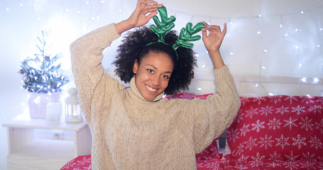 Image showing Playful young woman wearing green reindeer antlers