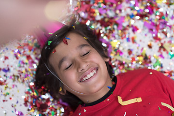 Image showing kid blowing confetti while lying on the floor