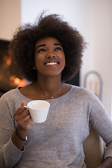 Image showing black woman drinking coffee in front of fireplace