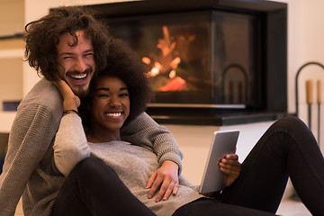 Image showing multiethnic couple using tablet computer on the floor