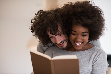 Image showing multiethnic couple hugging in front of fireplace