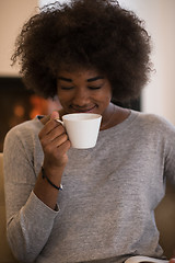 Image showing black woman reading book  in front of fireplace