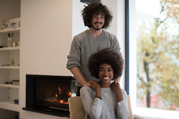 Image showing multiethnic couple hugging in front of fireplace