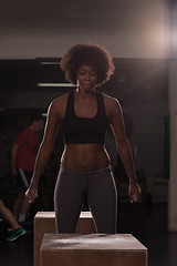 Image showing black female athlete is performing box jumps at gym