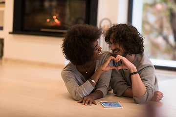 Image showing multiethnic couple showing a heart with their hands on the floor