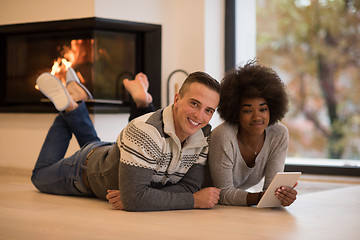 Image showing multiethnic couple using tablet computer on the floor