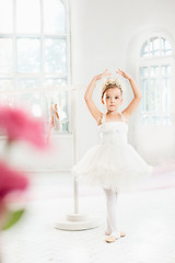 Image showing Little ballerina girl in a tutu. Adorable child dancing classical ballet in a white studio.