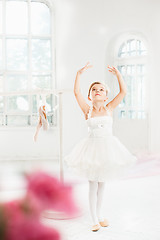 Image showing Little ballerina girl in a tutu. Adorable child dancing classical ballet in a white studio.