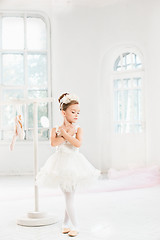 Image showing Little ballerina girl in a tutu. Adorable child dancing classical ballet in a white studio.