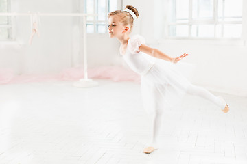 Image showing Little ballerina girl in a tutu. Adorable child dancing classical ballet in a white studio.