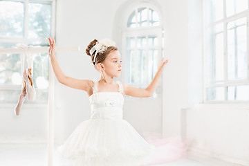 Image showing Little ballerina girl in a tutu. Adorable child dancing classical ballet in a white studio.