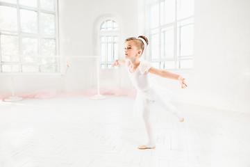 Image showing Little ballerina girl in a tutu. Adorable child dancing classical ballet in a white studio.