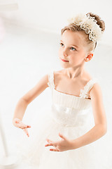 Image showing Little ballerina girl in a tutu. Adorable child dancing classical ballet in a white studio.