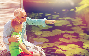 Image showing grandfather and grandson sitting on river berth