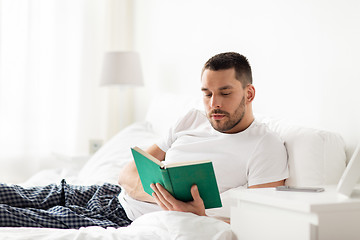 Image showing man reading book in bed at home