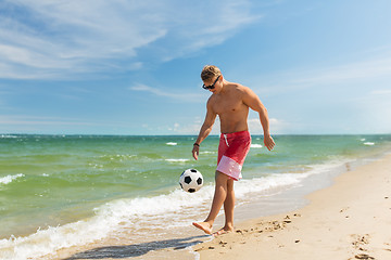 Image showing young man with ball playing soccer on beach