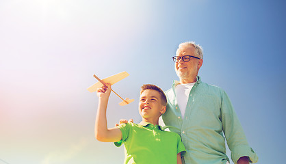 Image showing senior man and boy with toy airplane over sky