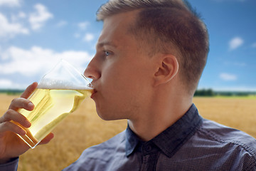 Image showing close up of young man drinking beer from glass