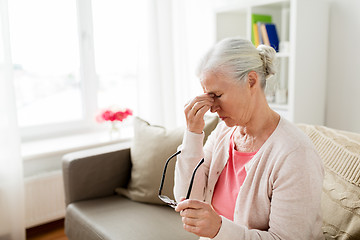 Image showing senior woman with glasses having headache at home