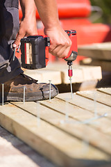 Image showing Carpenter working with an electric screwdriver.