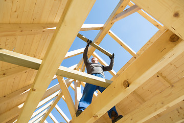 Image showing Builder at work with wooden roof construction.