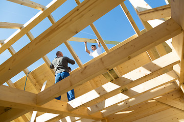 Image showing Builders at work with wooden roof construction.