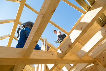 Image showing Builders at work with wooden roof construction.