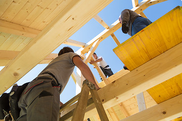 Image showing Builders at work with wooden roof construction.