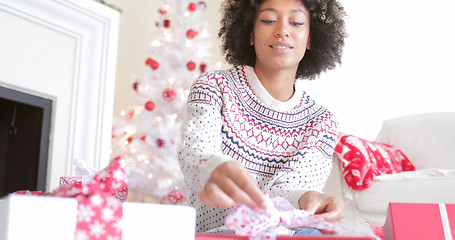 Image showing Young woman opening her Christmas gifts