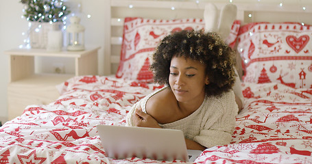 Image showing Beautiful woman reading something on laptop in bed