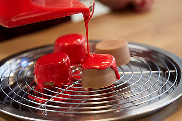 Image showing jug pouring glaze to cakes at pastry shop