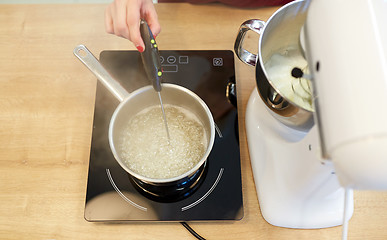 Image showing chef measuring temperature in syrup at kitchen