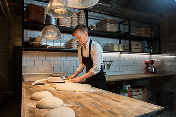 Image showing baker portioning dough with bench cutter at bakery