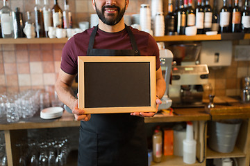Image showing happy man or waiter with blank blackboard at bar