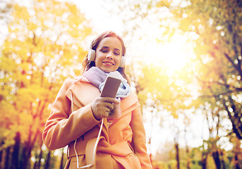 Image showing woman with smartphone and earphones in autumn park