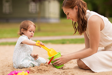 Image showing happy mother with baby girl playing in sandbox