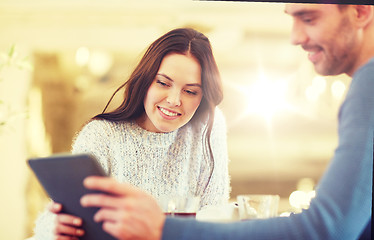 Image showing happy couple with tablet pc drinking tea at cafe